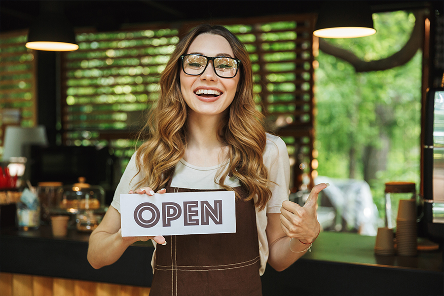 business woman holding open sign after taking out a commercial mortgage
